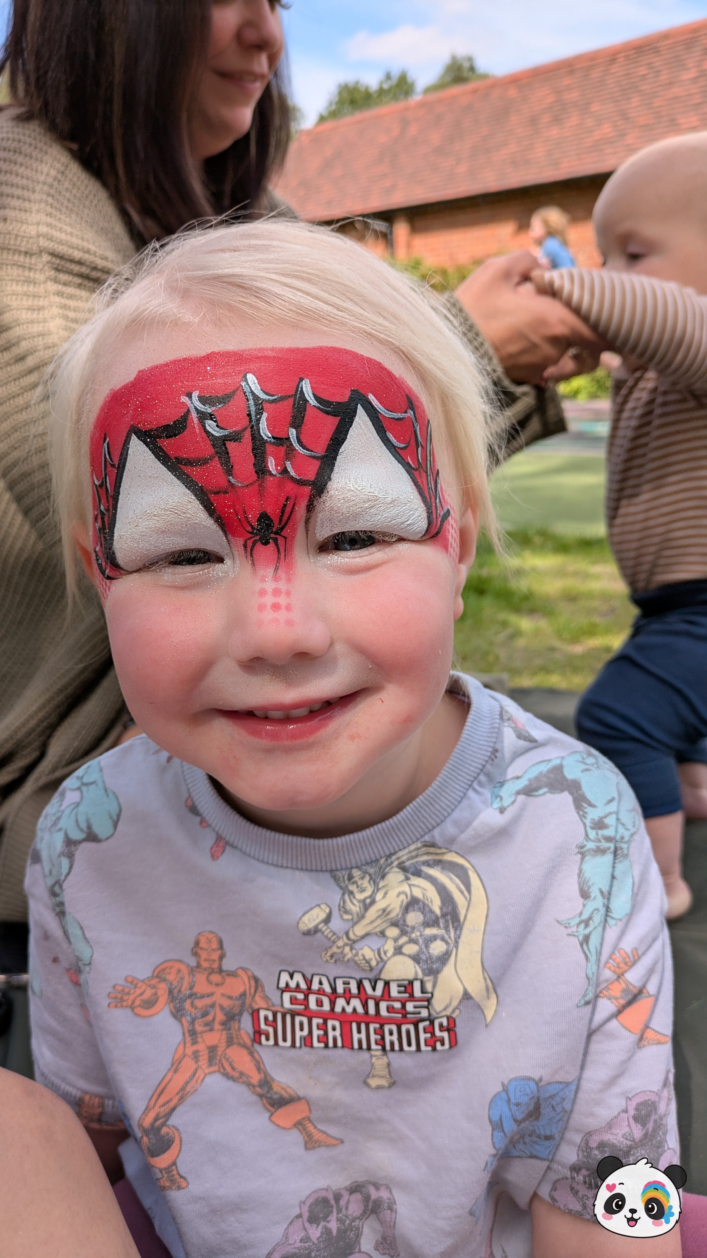 Red and black spider web face paint covering the forehead and eyes with white eye accents and a small spider detail on the nose.