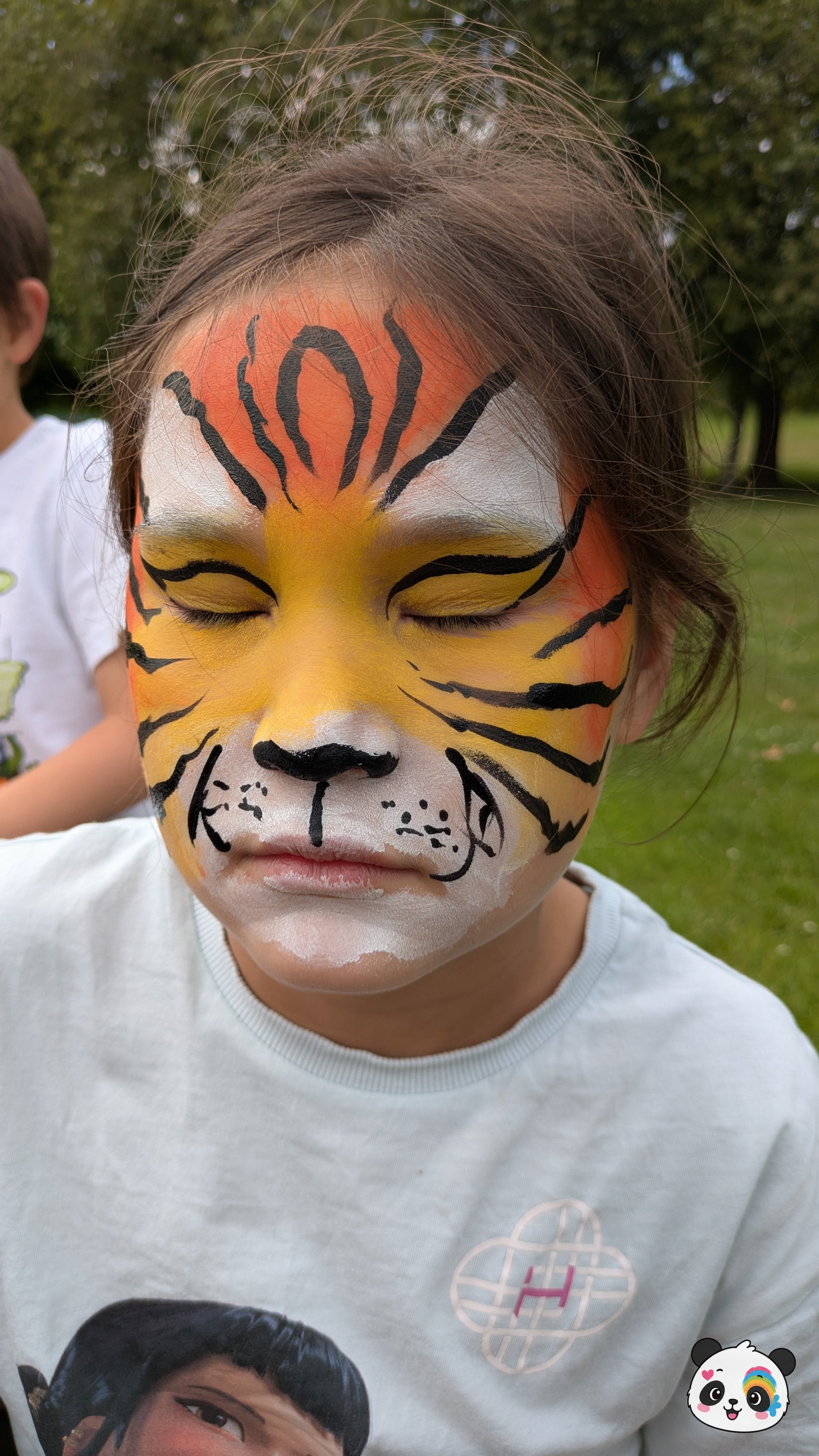 Orange, yellow, and white tiger face paint with bold black stripes covering the forehead, eyes, and cheeks.