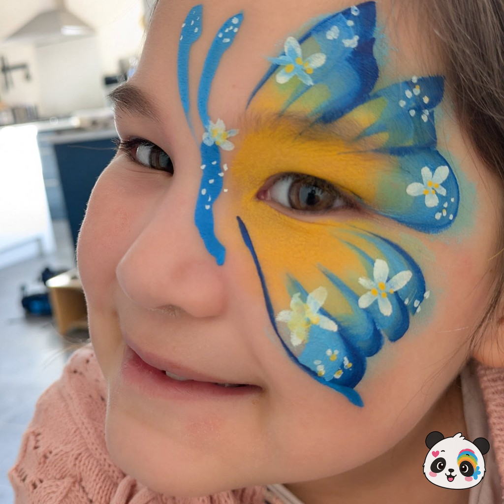 Blue and yellow butterfly wing face paint with white flowers