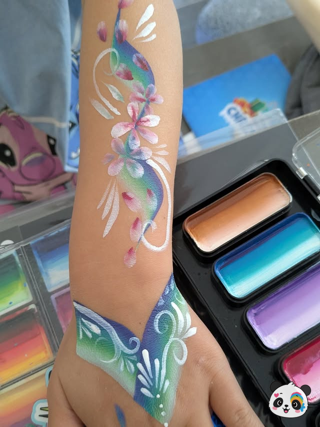 Teal and purple floral arm painting with butterfly-style hand art