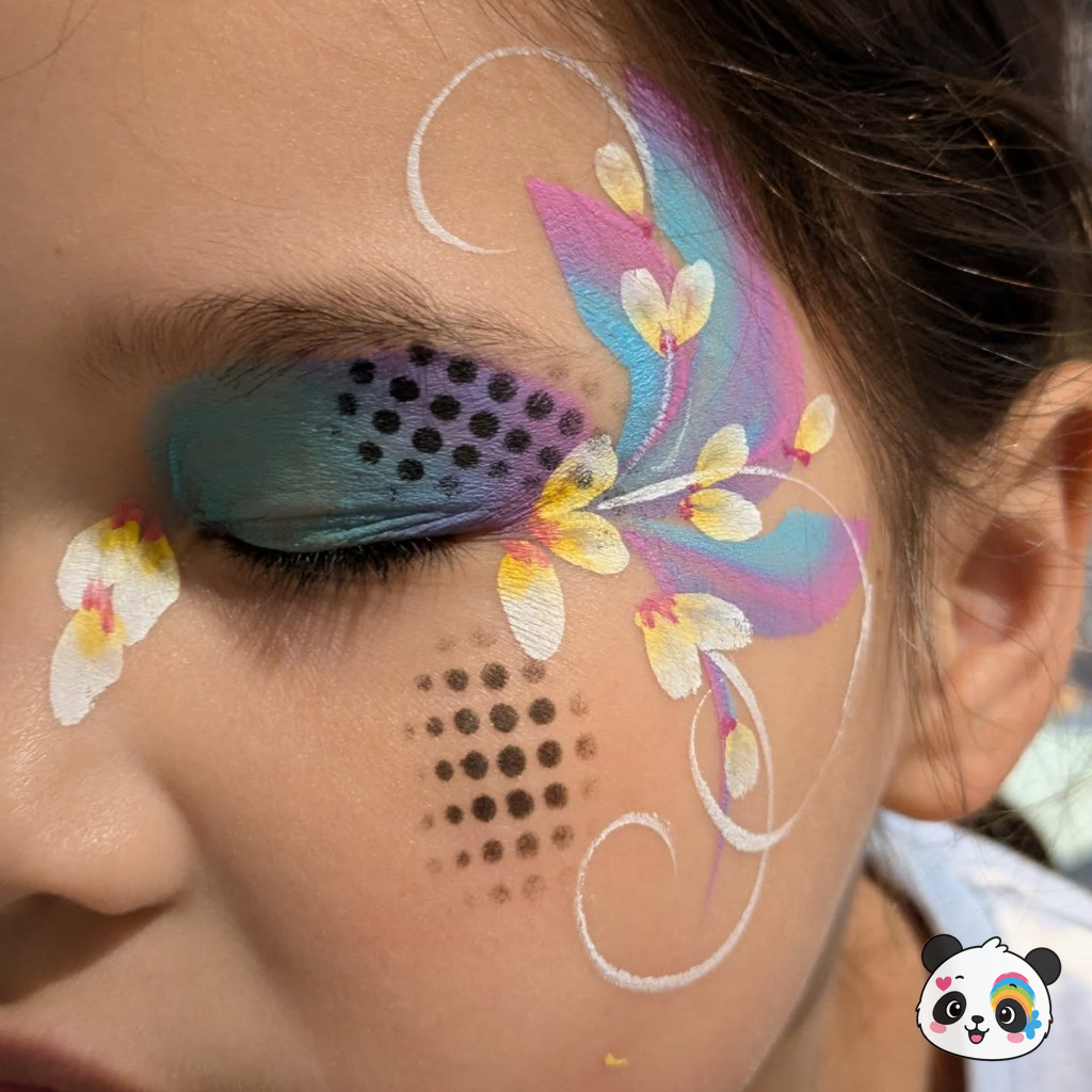 Teal and purple floral face paint with white blossoms around the eye