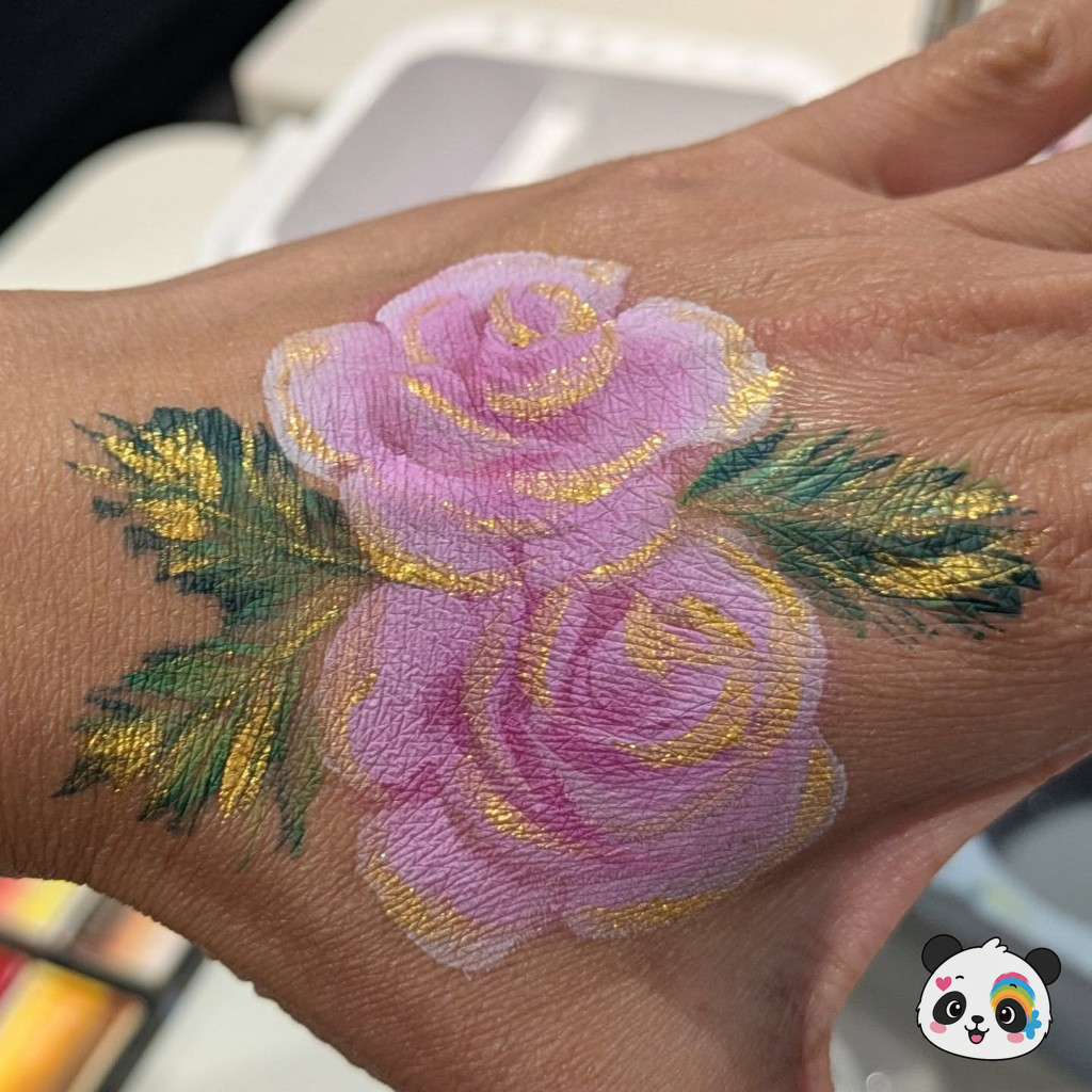 Pink roses with gold highlights painted on the back of a hand