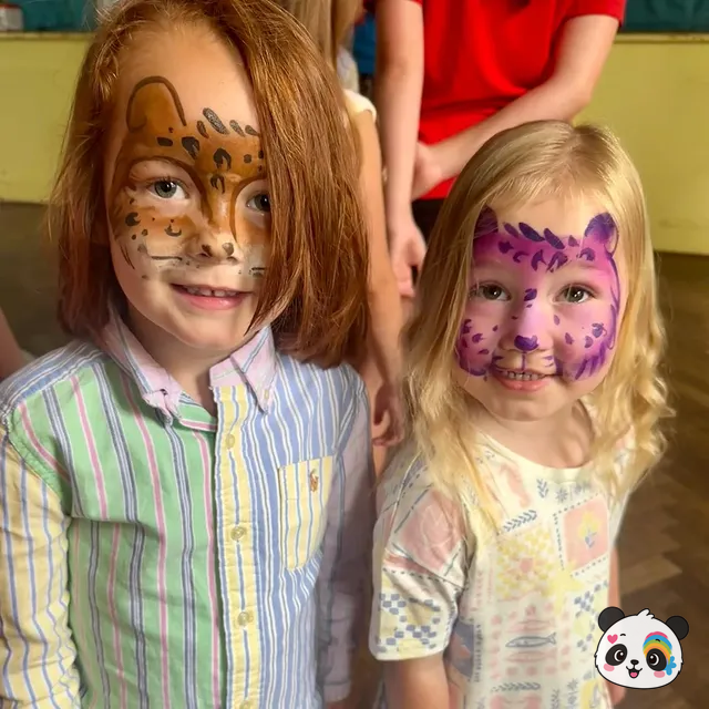 Two children with leopard and cheetah face paint at an indoor event