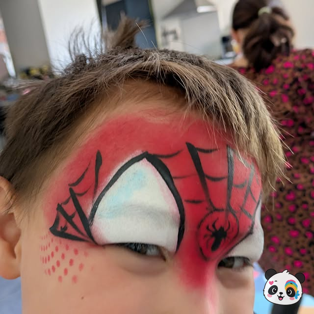 Spider-Man face paint with web pattern and spider detail on a child